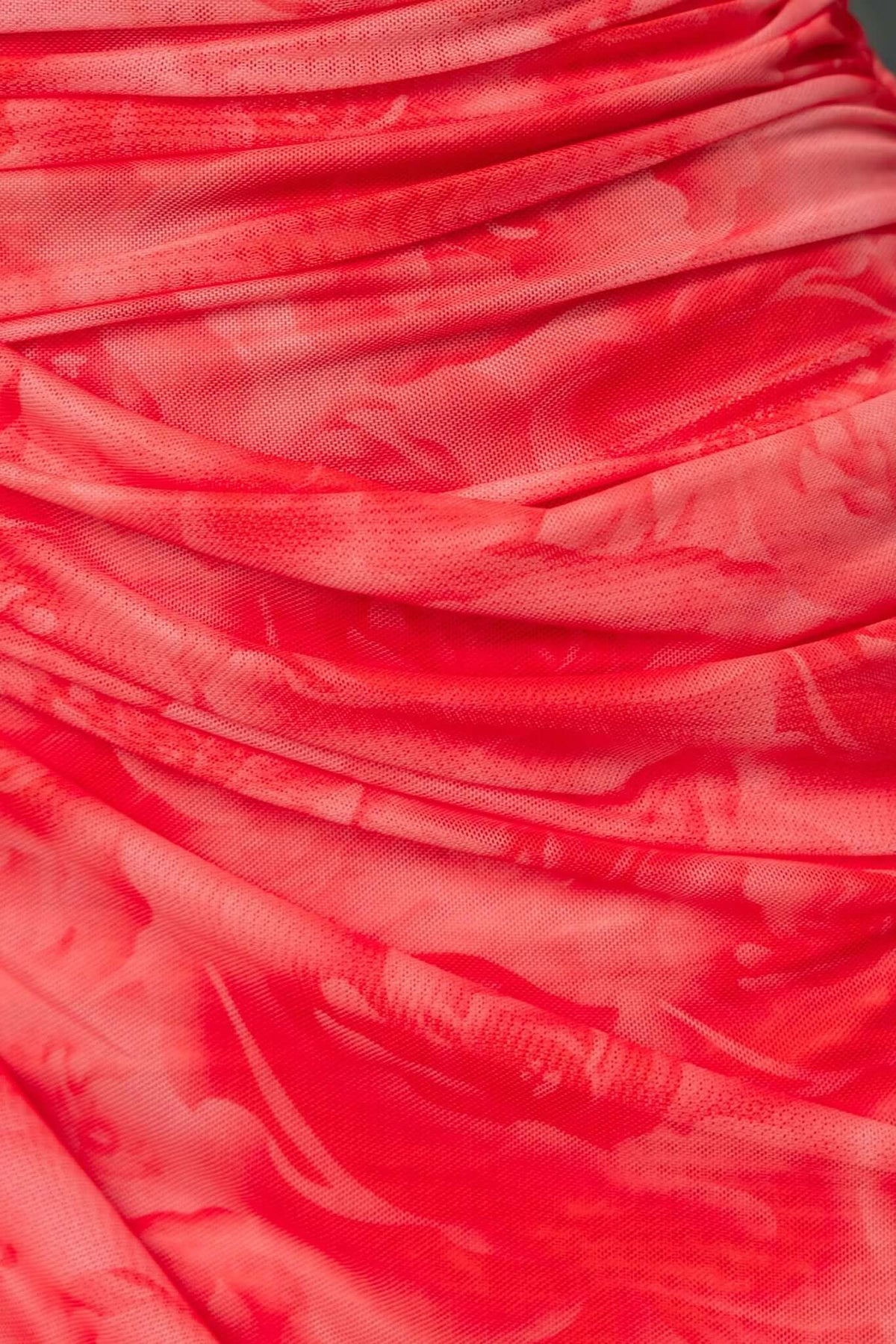 Close-up of the ruched fabric detail on a bright red Saloni maxi dress showcasing floral patterns and texture.