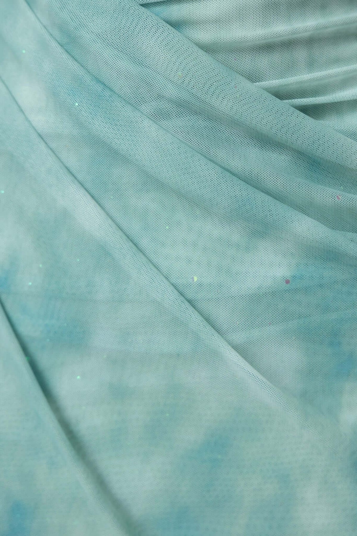 Close-up of light turquoise mesh fabric with glitter, showcasing soft draping and textures for Saloni Maxi Dress.