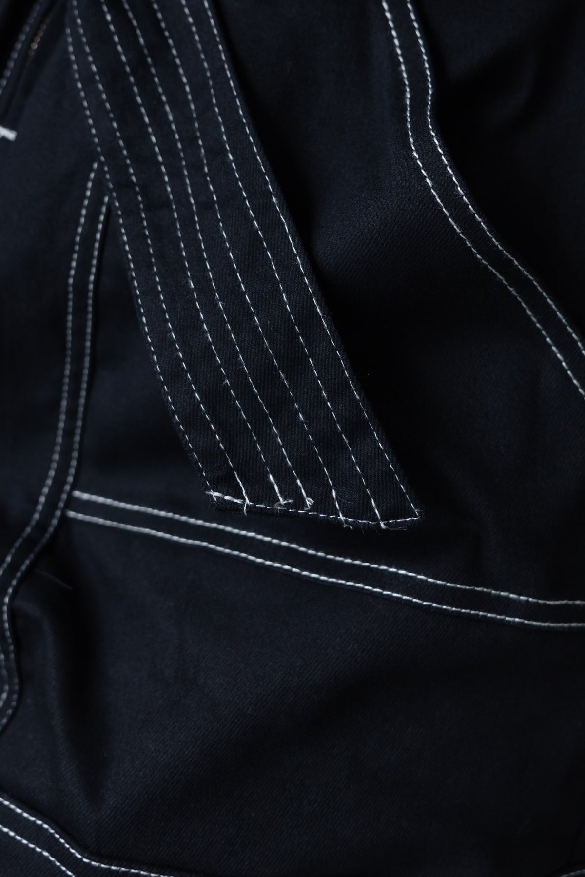Close-up of black denim fabric with white stitching detail, highlighting the Pina Denim Playsuit design.