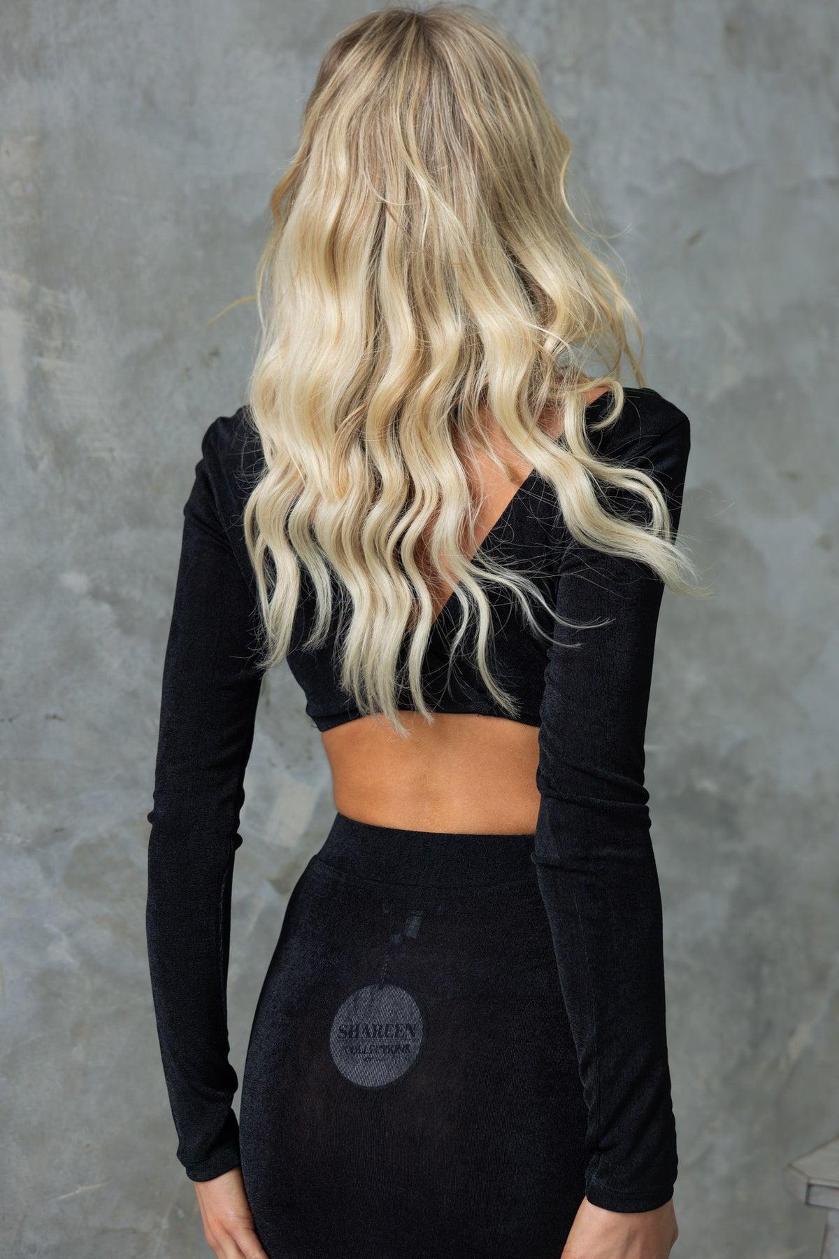 Back view of a model wearing a black Burnette top with long sleeves and a cropped design, showing stylish hair and a sleek look.