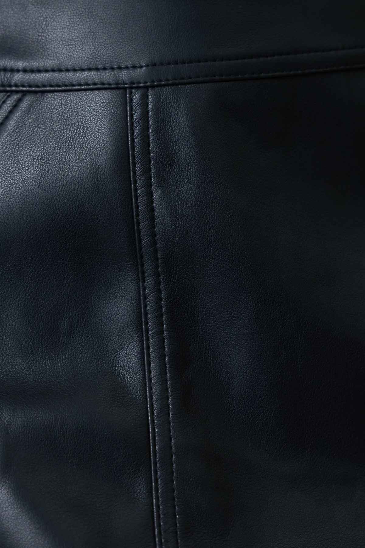 Close-up of Inoe skirt showing faux leather texture and detailing in black color.