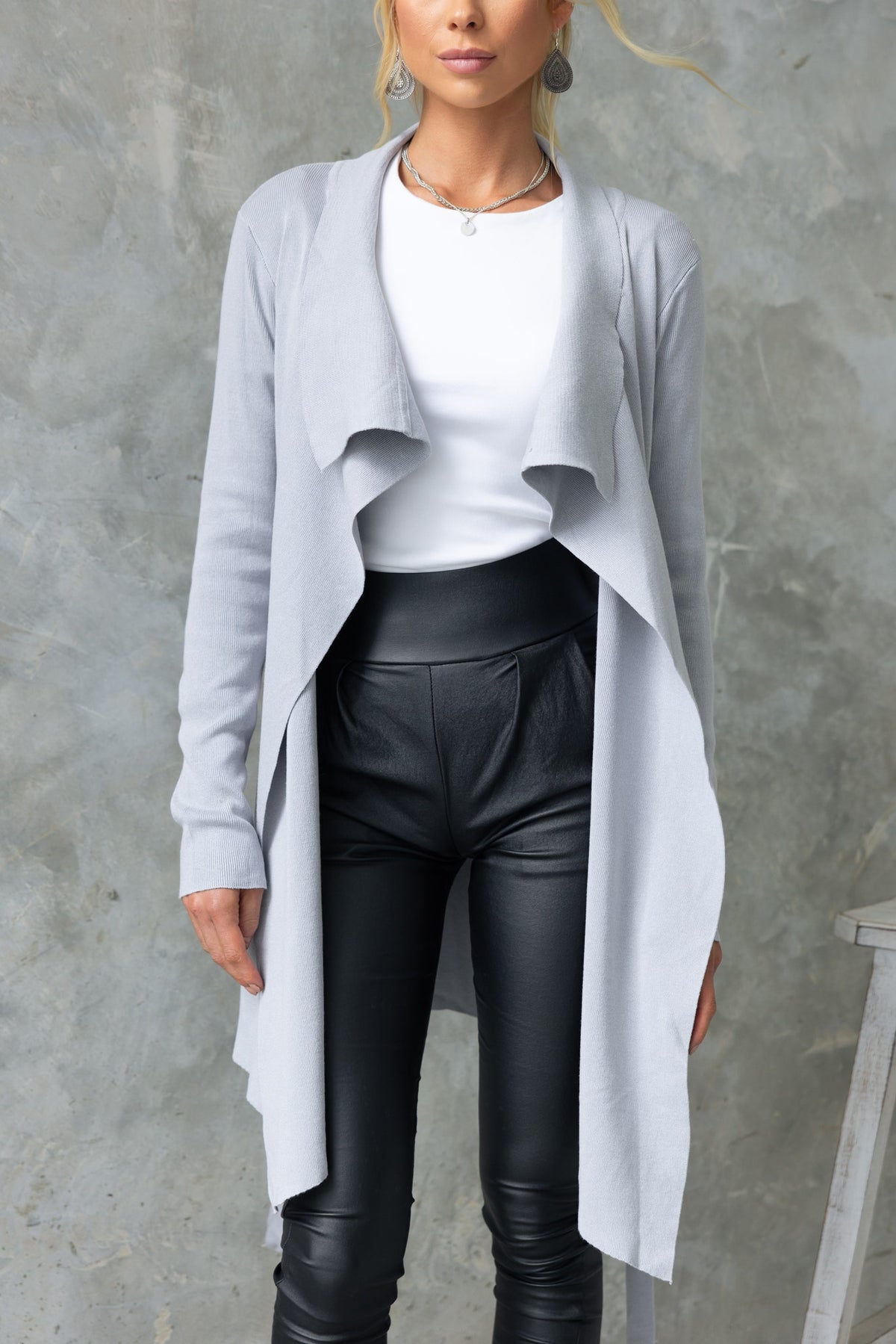 Woman wearing a light gray Acaia cardigan over a white top, paired with black leather pants.