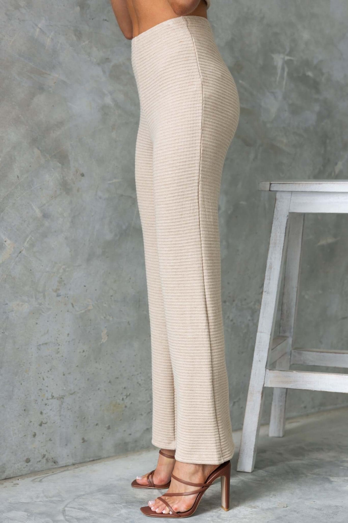 Side view of Xandra Pants in cream, featuring mid-high waist, elastic waistband, and drop-crotch style with knit material.