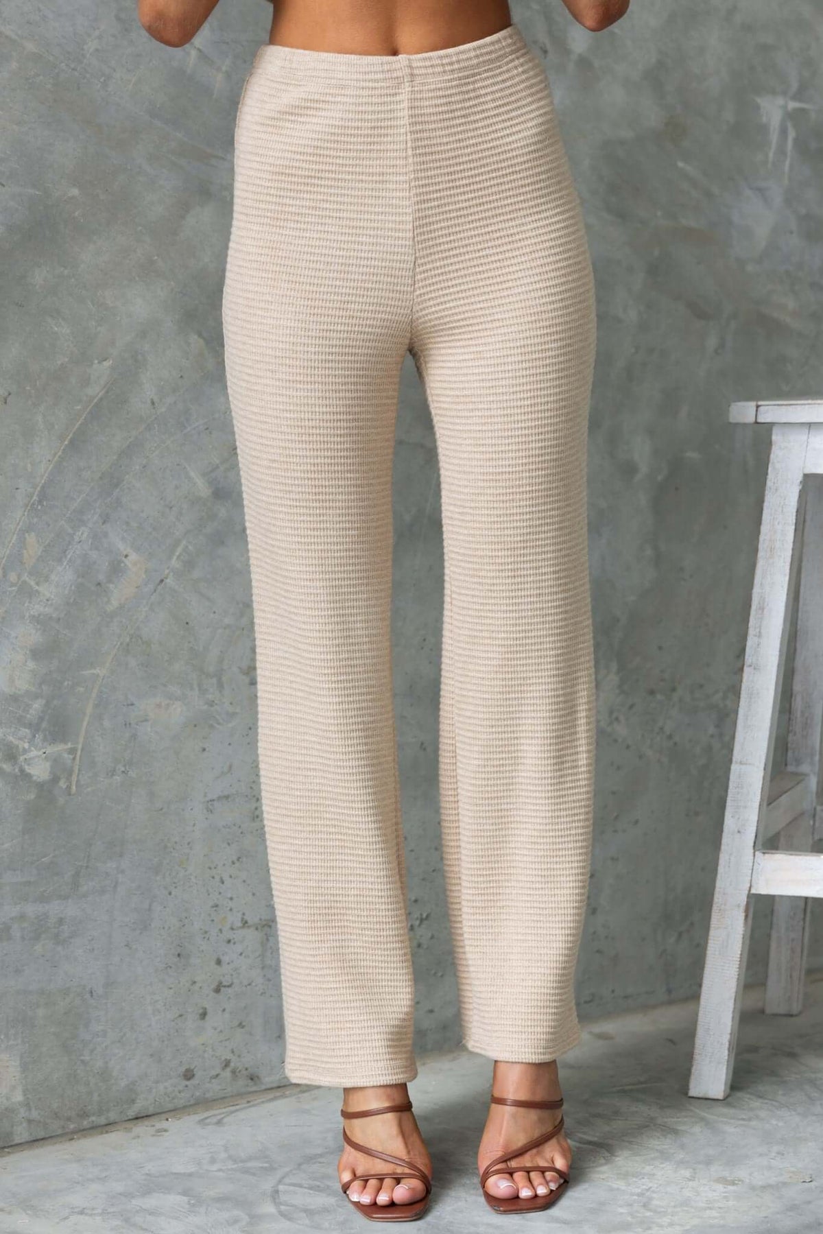 Xandra Pants featuring a mid-high waist, elastic waistband, and drop-crotch style in a beige knit material.