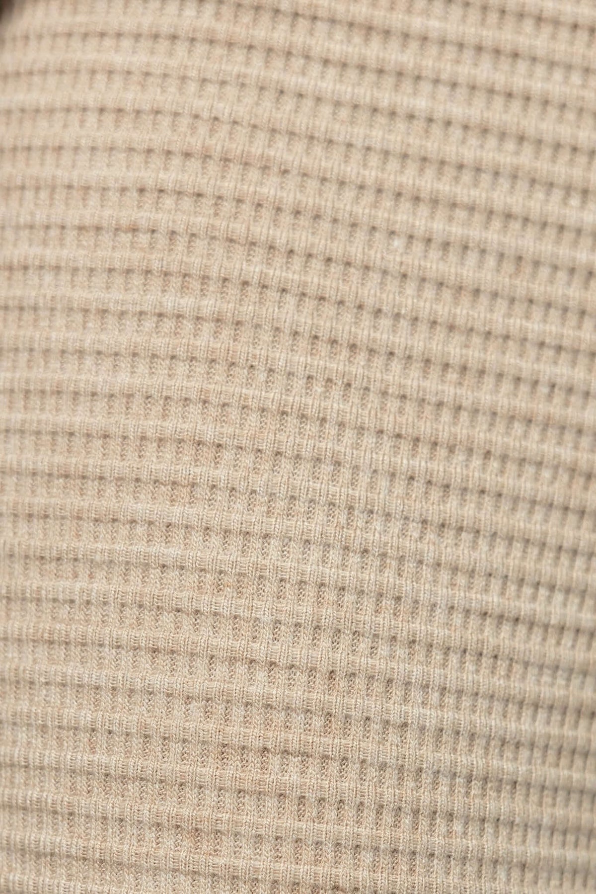 Close-up of Xandra Pants fabric texture in beige, showcasing knit material with a ribbed pattern.