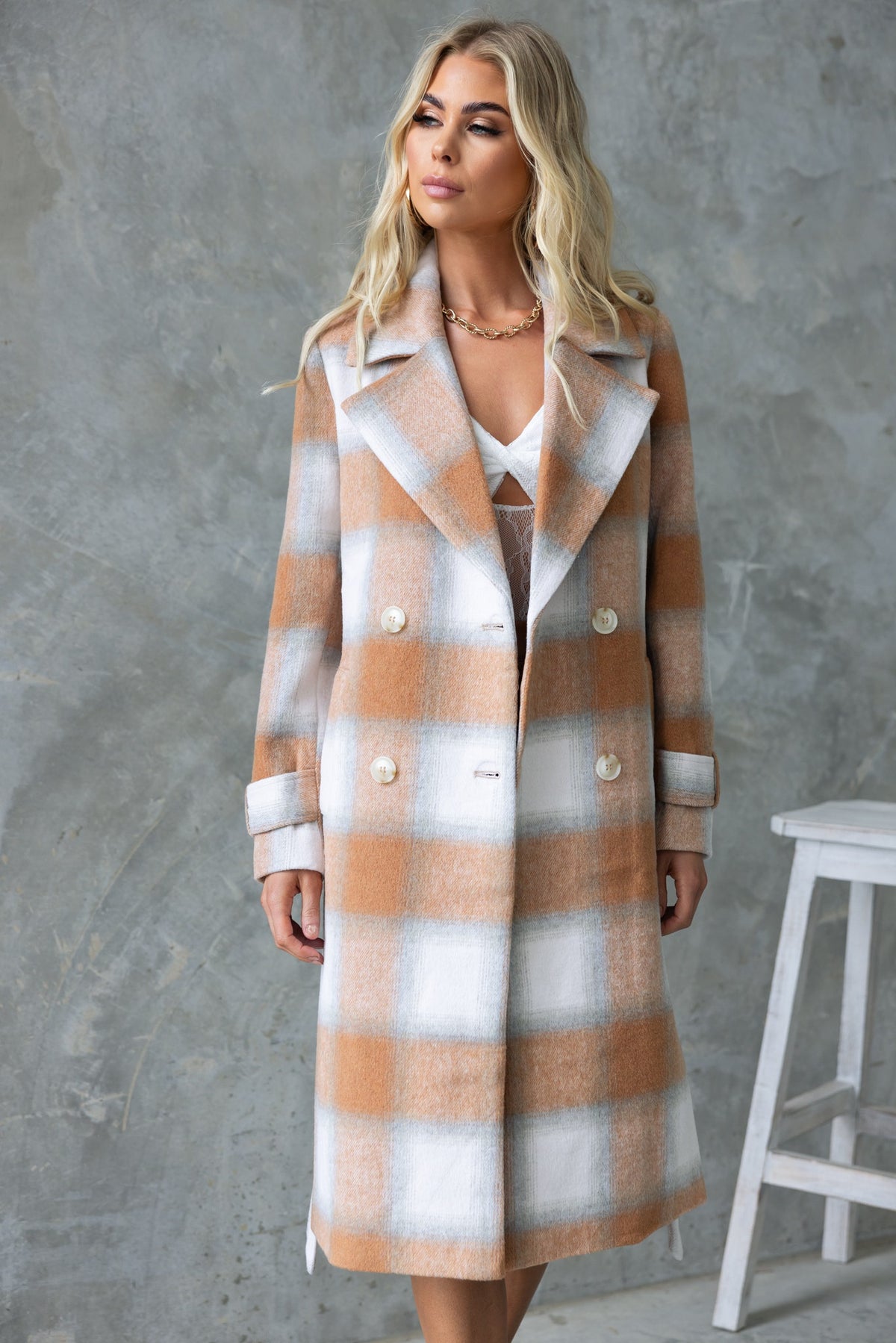 Amalie Coat in beige and white check pattern, featuring a longline fit, collar, button-up front, and pockets.