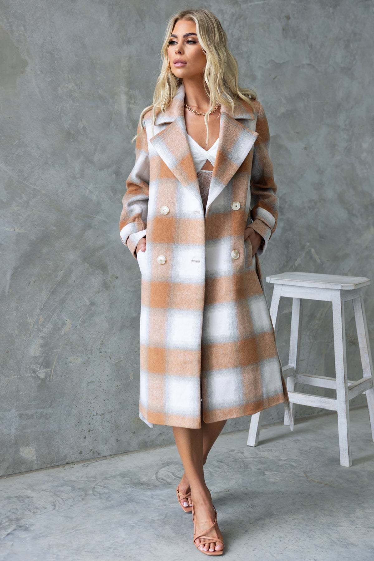 Stylish Amalie Coat in check pattern, featuring a longline fit, collar, button-up front, and pockets, perfect for any occasion.