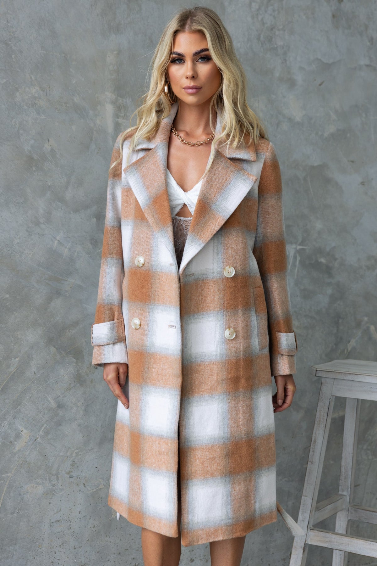 Amalie Coat in plaid pattern, featuring longline fit, collar, button-up front, and pockets, modeled by a woman.