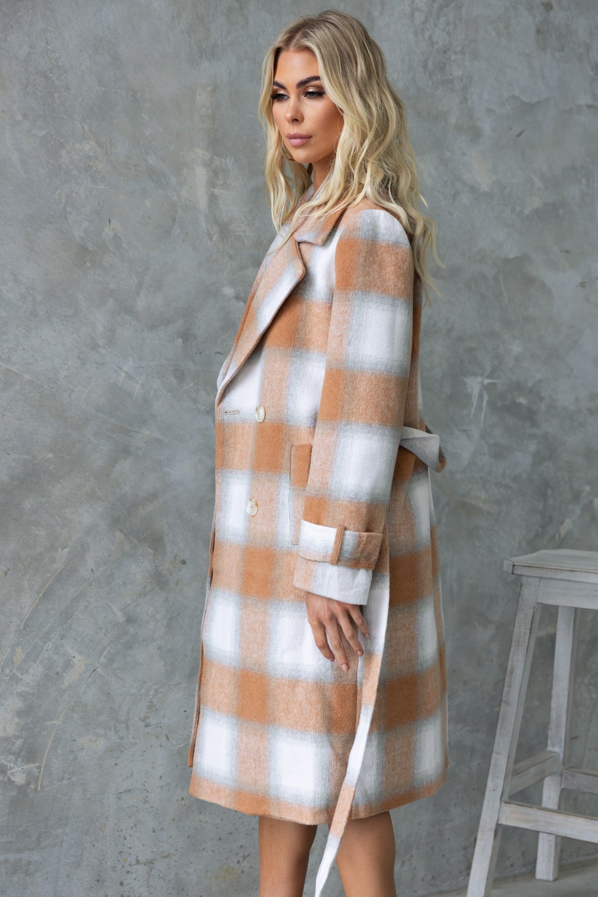 Model wearing the Amalie longline coat with plaid pattern, featuring a collar, lapel, and removable fabric tie.