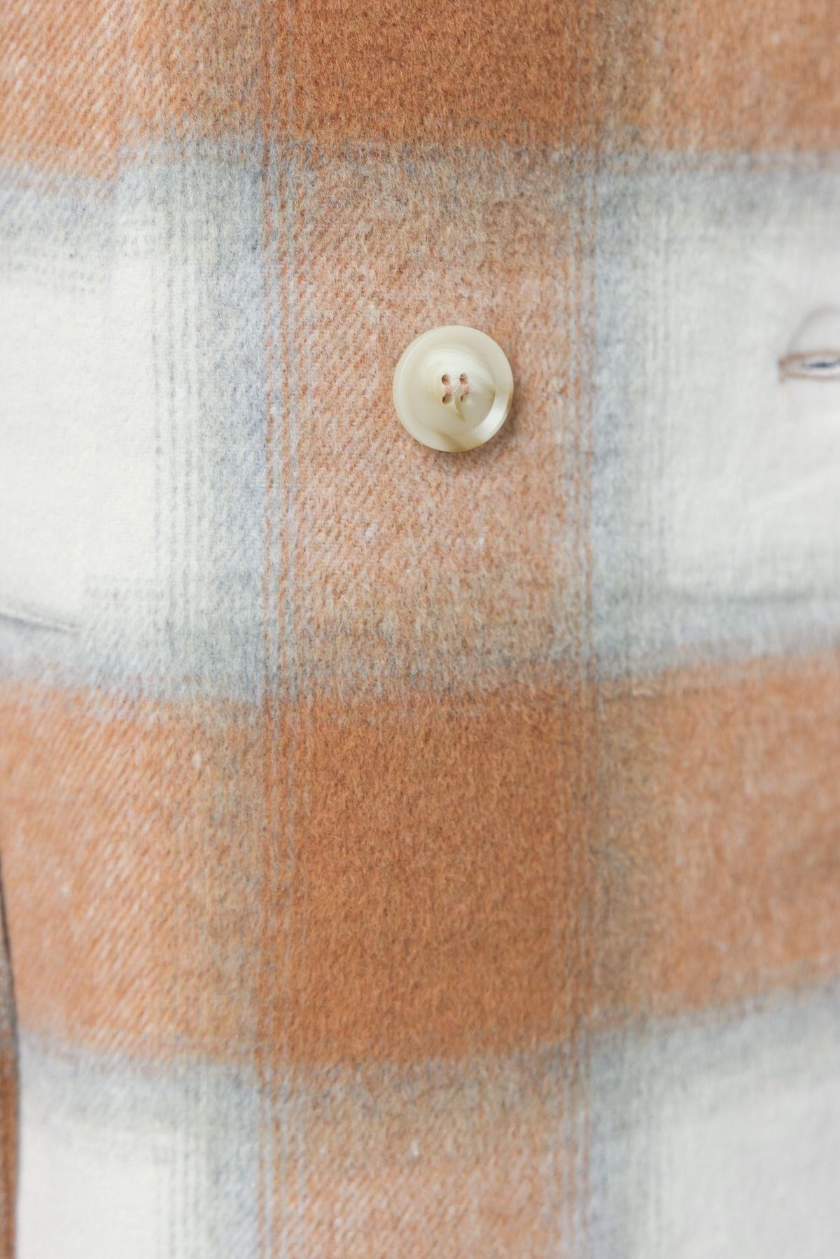 Close-up of Amalie Coat button and fabric, featuring a brown and white check pattern.
