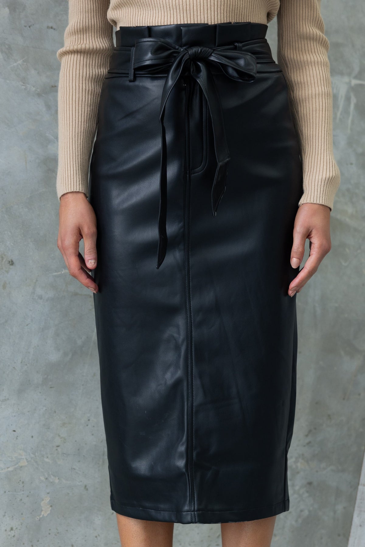 Black midi skirt with removable tie and back split, made from faux leather, styled with a ribbed top.