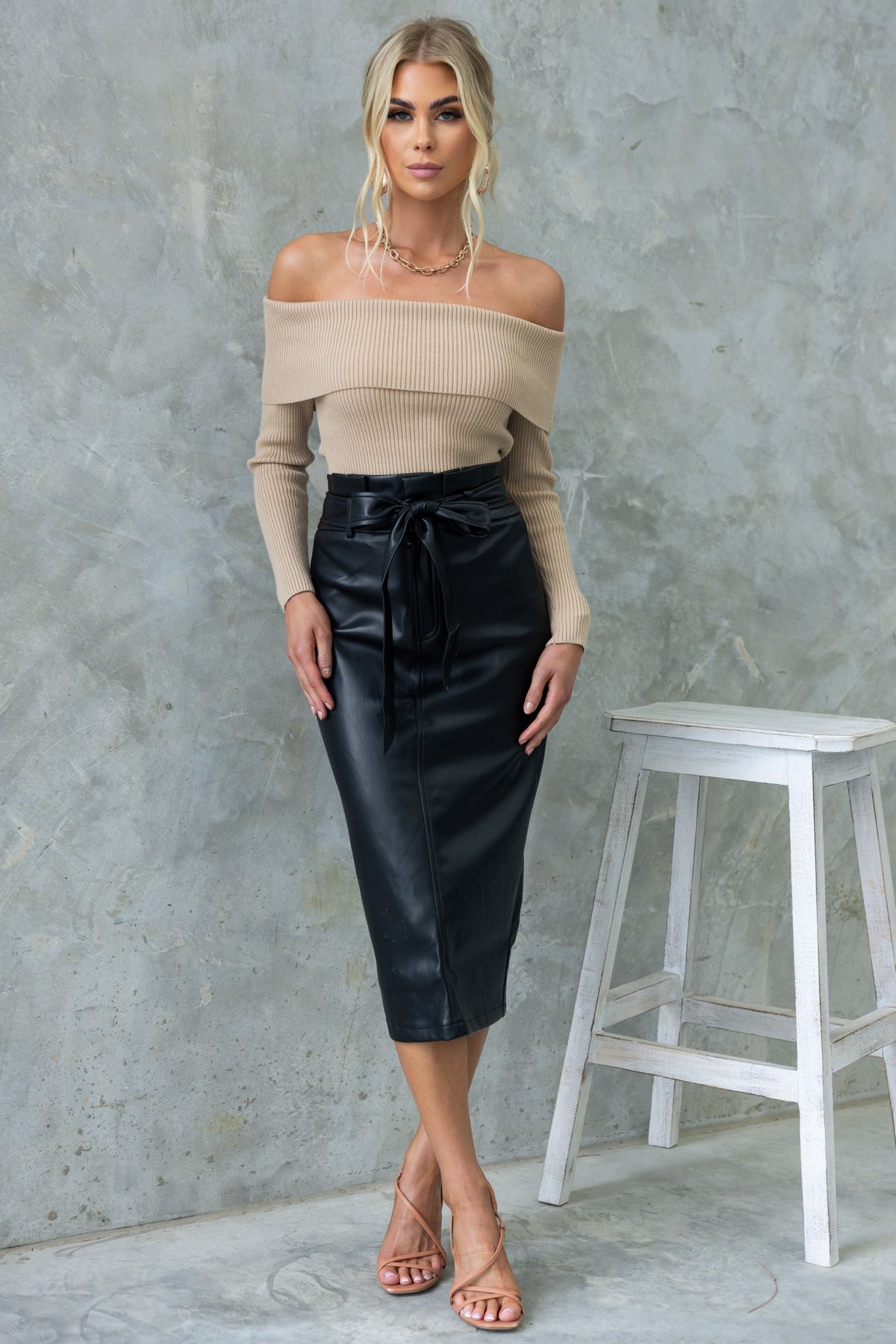 Model wearing Nerida Midi Skirt in faux leather with tie waist, showcasing mid-high fit and back split.