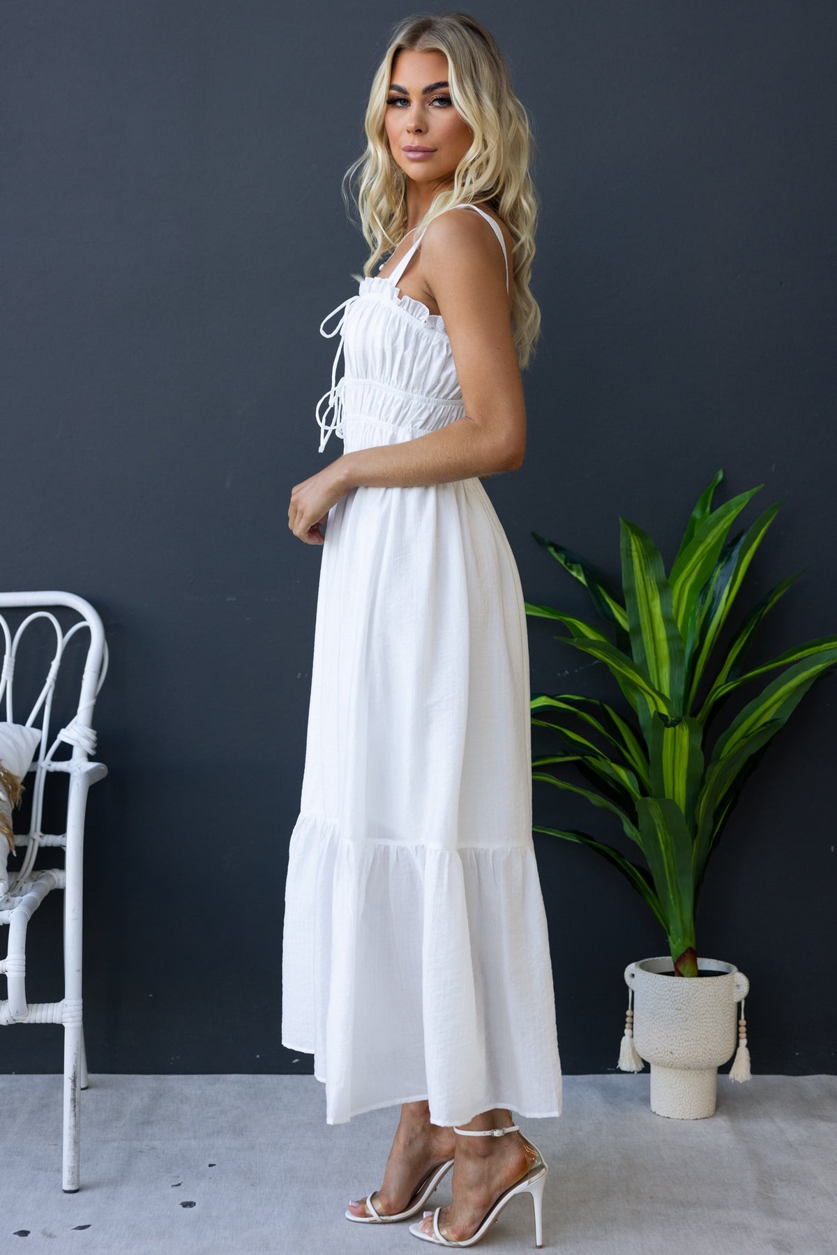 Shanina Midi Dress in white, featuring elastic bodice, tie details, and textured fabric, styled with heels.