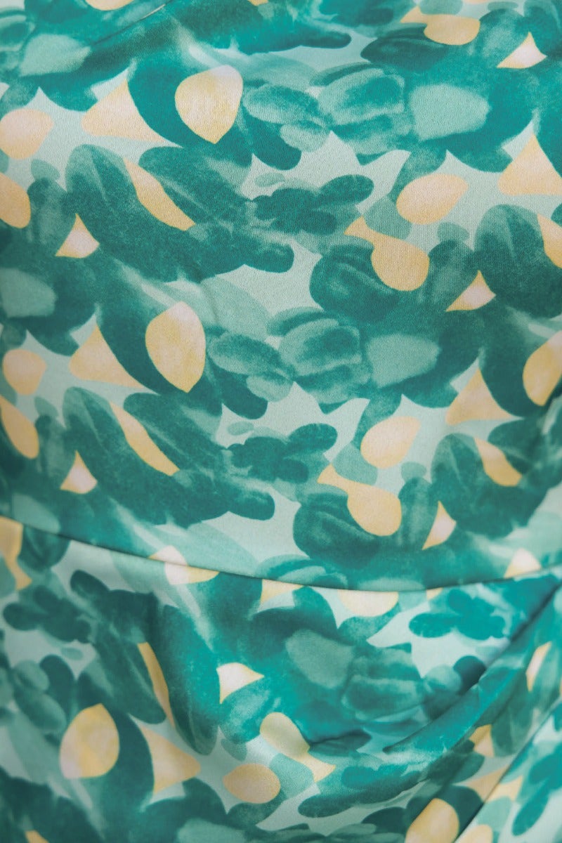 Close-up of Cordelia Dress fabric featuring a vibrant green and yellow floral pattern on a satin background.