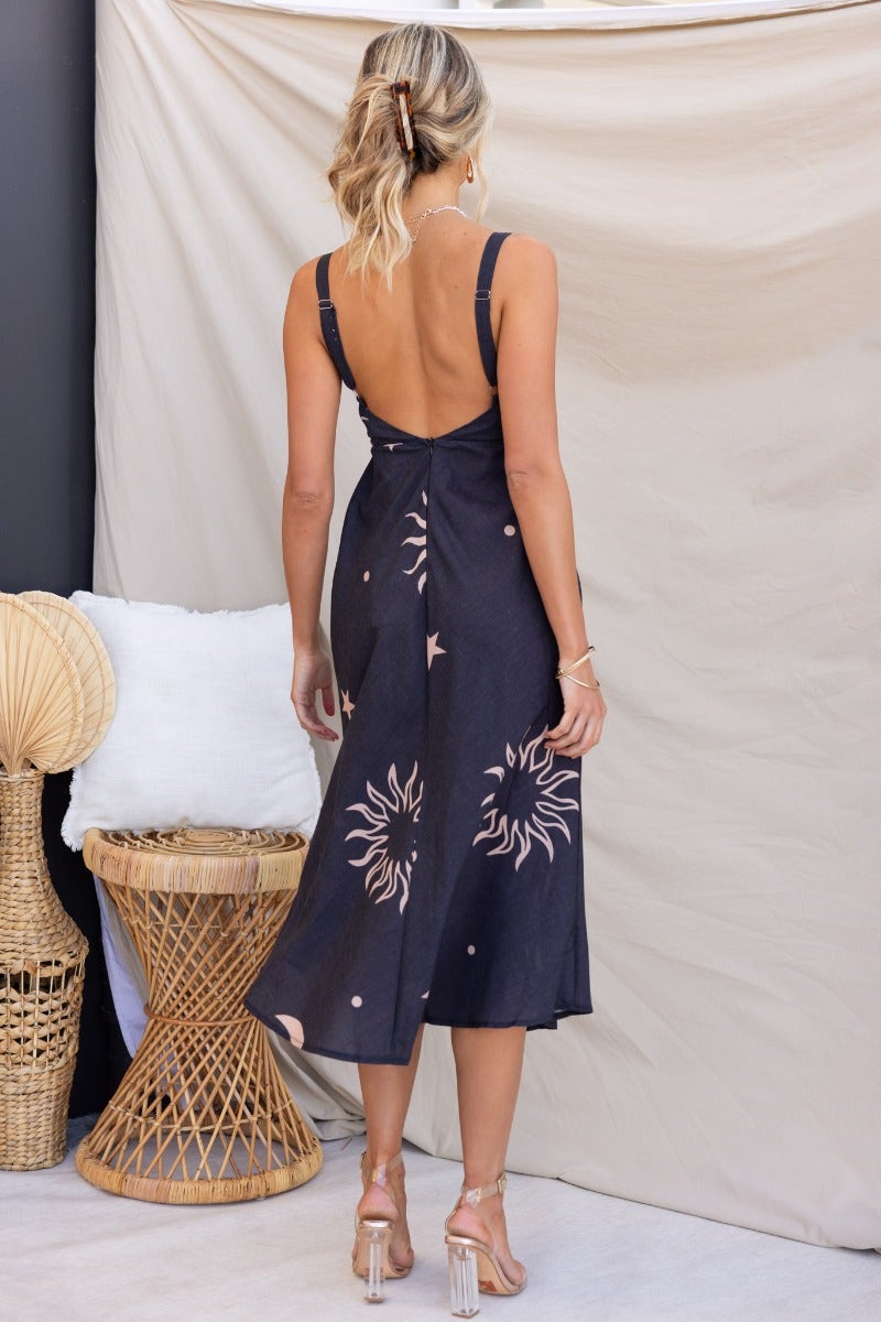 Back view of a faded black midi dress with sun print, featuring adjustable straps and a square neckline.