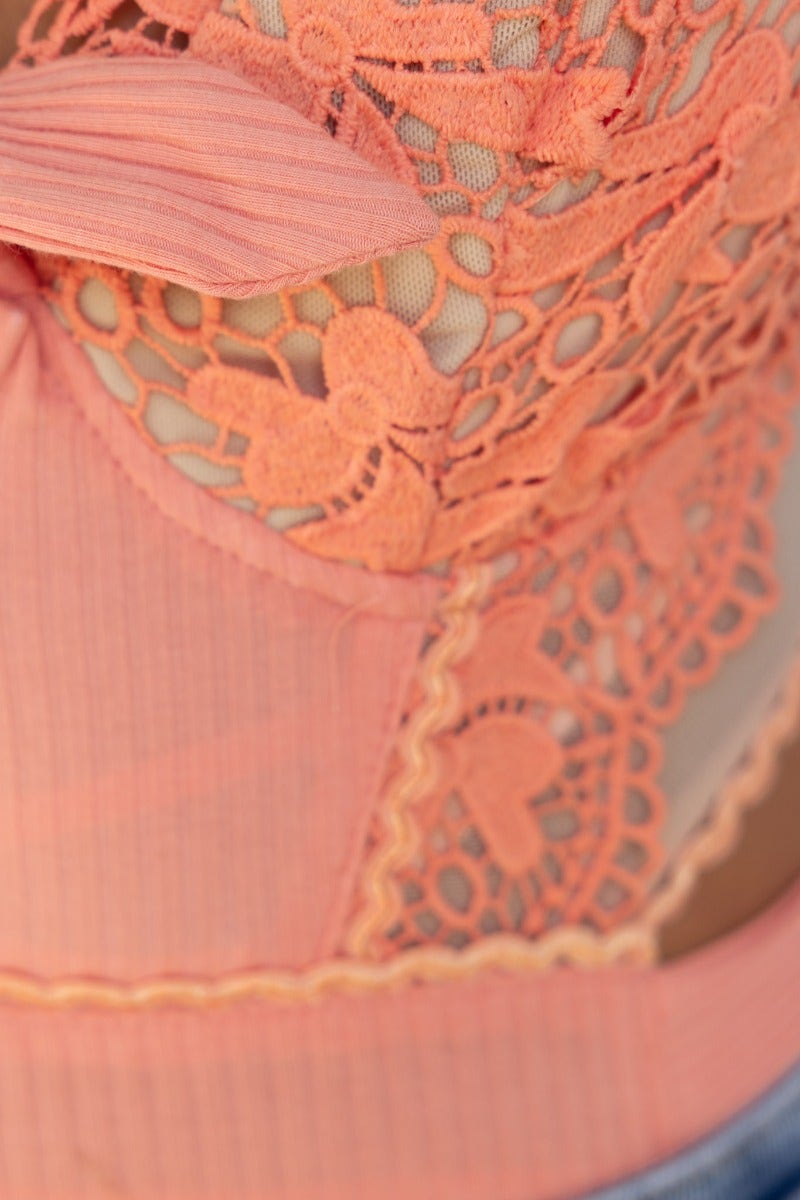 Close-up of Erith bodysuit in peach, featuring ribbed fabric and intricate lace detailing.