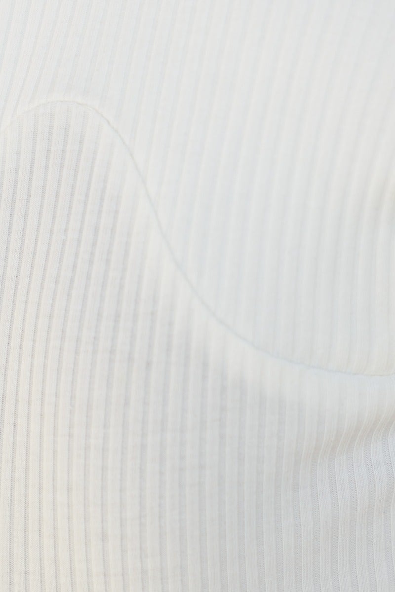 Close-up of ribbed texture on a white bodysuit, showcasing its soft material and unique design.