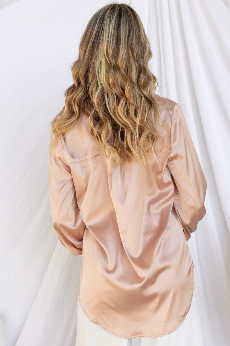 Back view of Daina Satin Shirt in soft peach, featuring relaxed fit and button-up design with elastic cuffs.