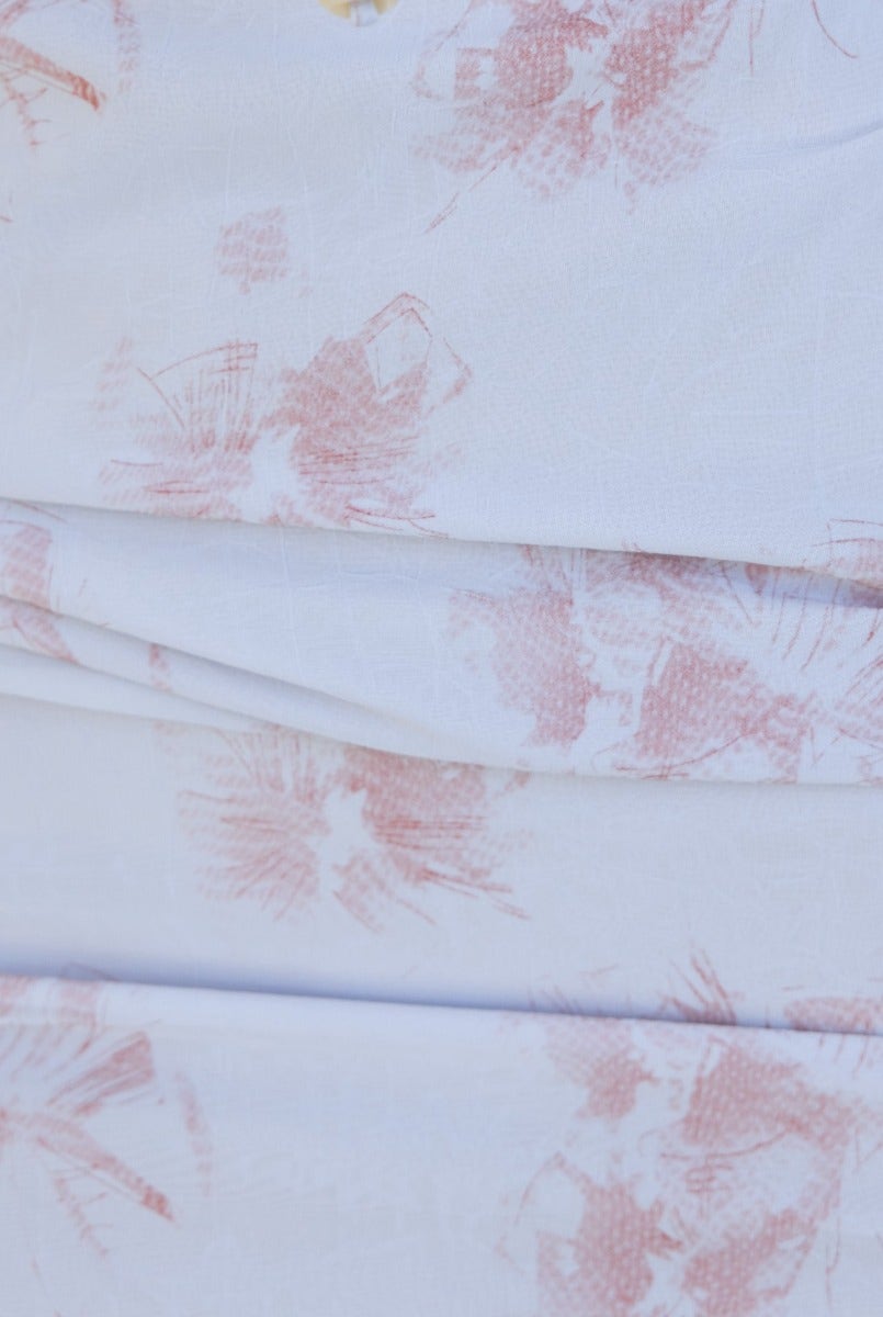 Close-up of soft white fabric with a delicate pink floral print, perfect for a beachside dress.