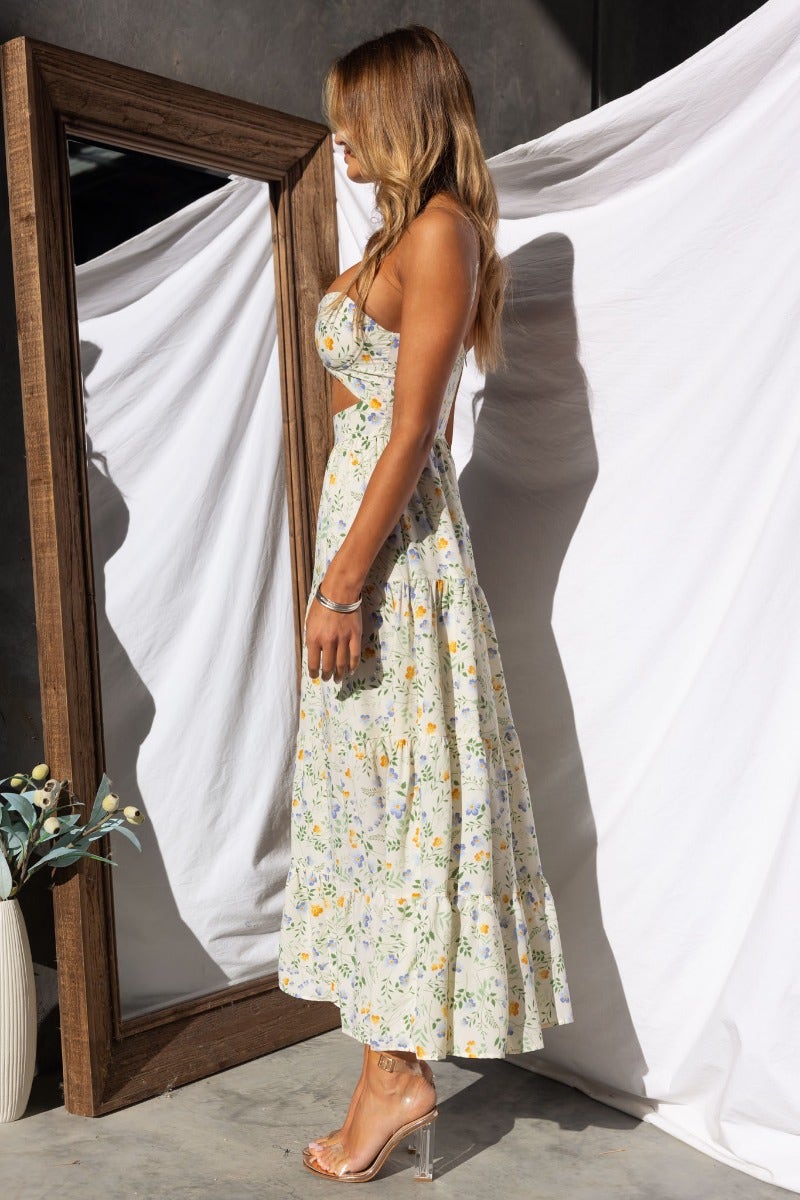 Side view of Klarie Maxi Dress featuring floral print, adjustable straps, and a cut-out waist in natural light.