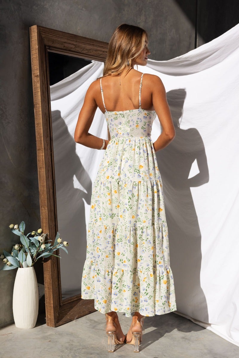Back view of a woman in a floral print Klarie maxi dress with adjustable straps and a cut-out waist.
