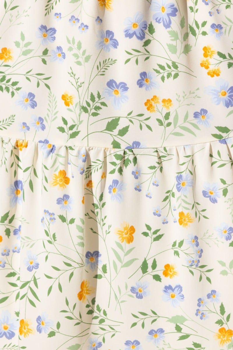 Floral print fabric detail of Klarie Maxi Dress featuring blue and yellow flowers on a cream background.