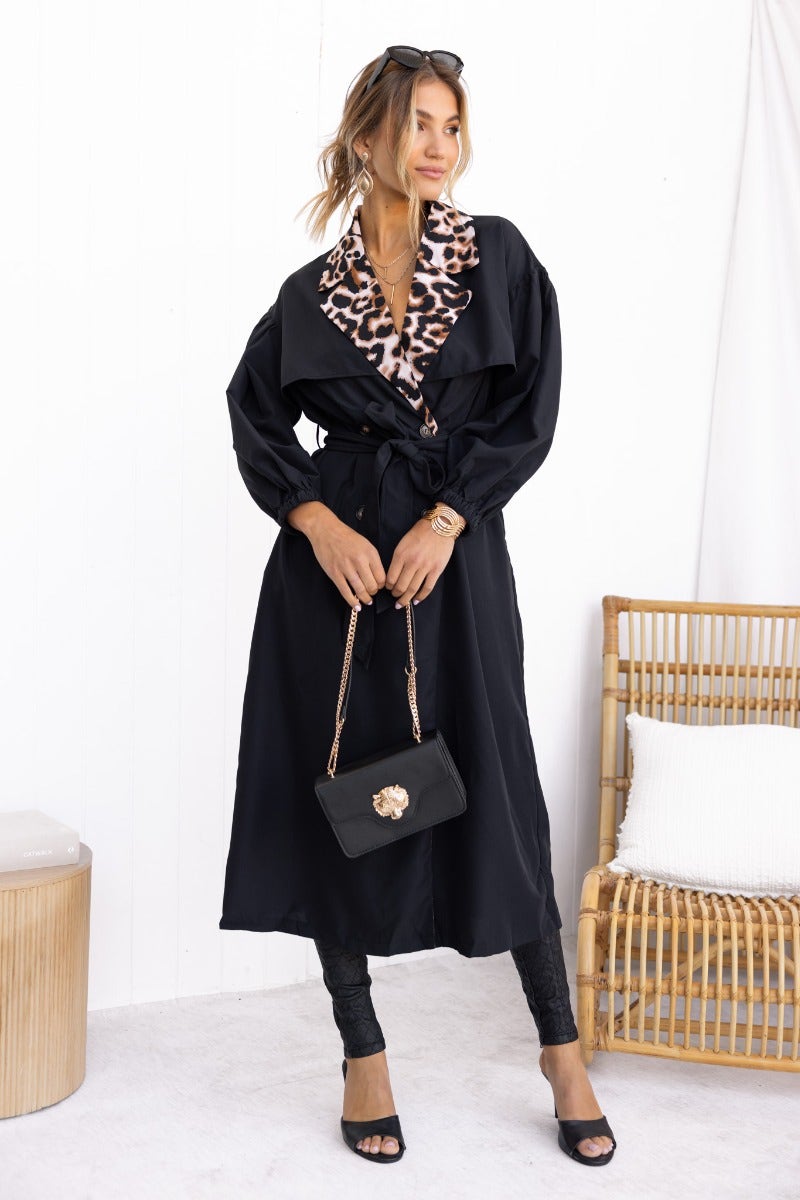 Stylish woman wearing an Oxley Coat with animal print collar, black trench coat and removable tie, perfect for any occasion.