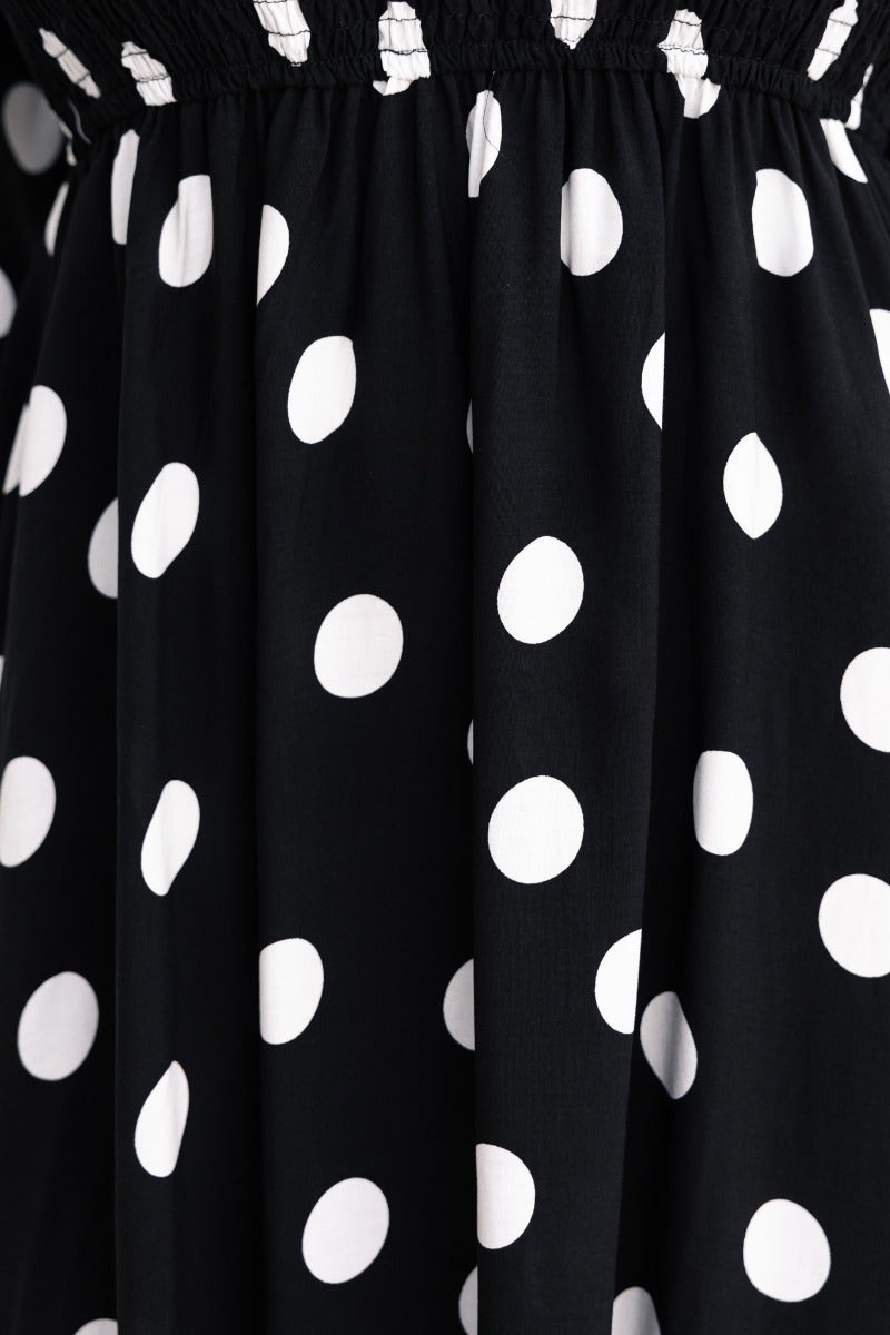 Close-up of black polka dot fabric showcasing the elastic bodice and relaxed fit of the Dostan Midi Dress.