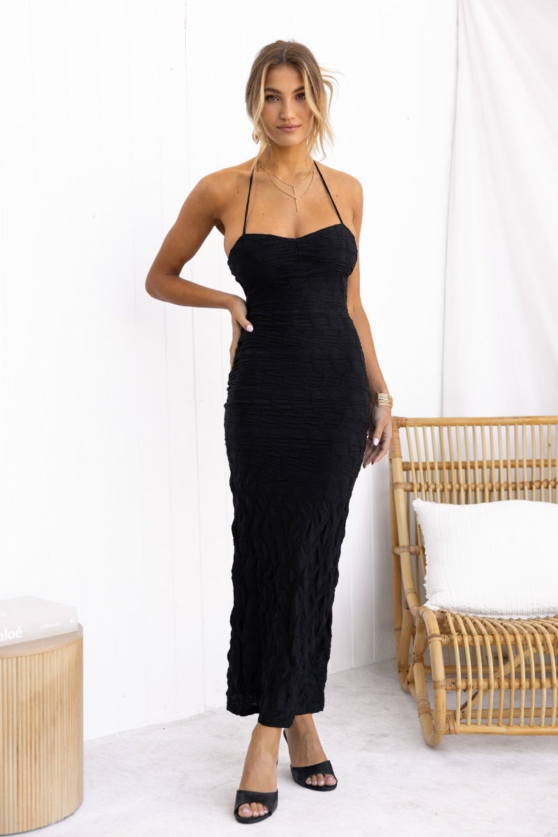Black maxi dress with textured fabric and adjustable halter neckline, featuring a back split and invisible zip.
