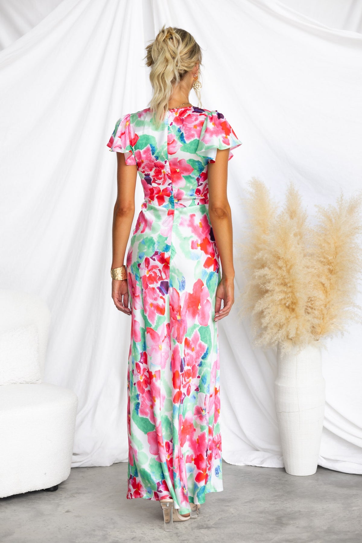 Back view of a woman wearing a floral satin Belmont Maxi Dress with cap sleeves and a flowing silhouette.