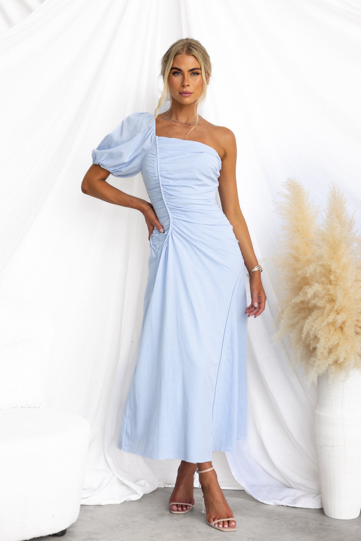 Model wearing a lavender haze cotton maxi dress with one-shoulder neckline and ruched detailing, set against a light backdrop.