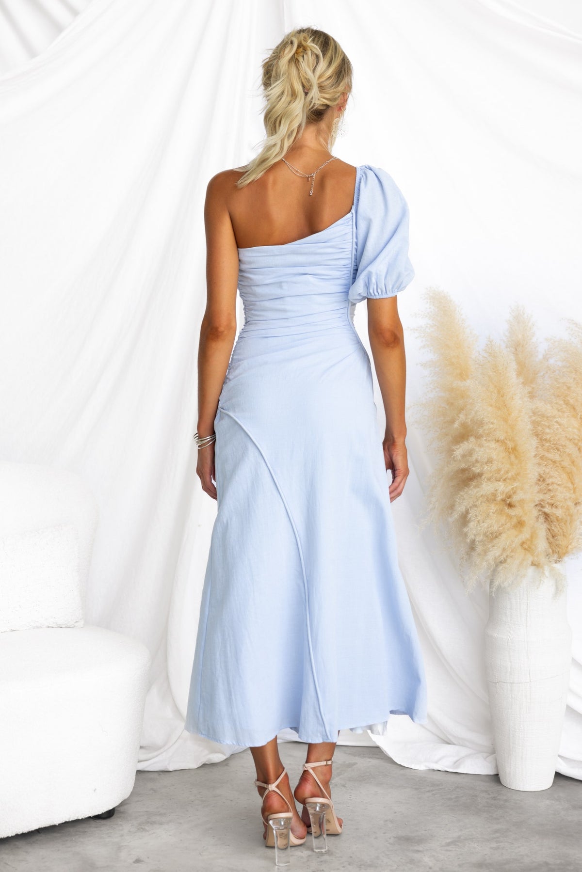 Model wearing a lavender haze maxi dress with one-shoulder neckline and puff sleeve, showcasing a stylish back view.