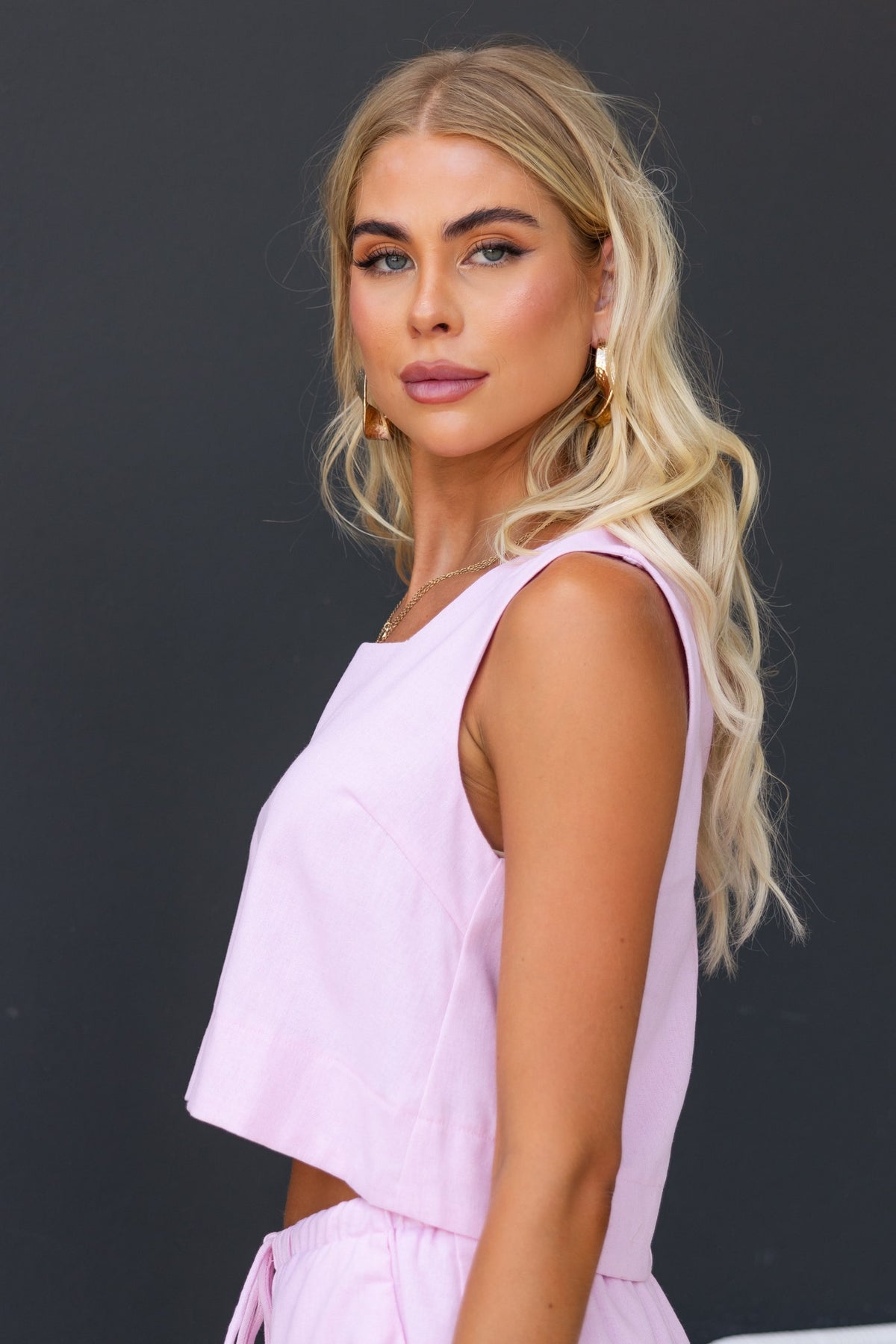Model wearing the Tiann Top, a pink square neckline top with a linen feel, showcasing a stylish and chic look.