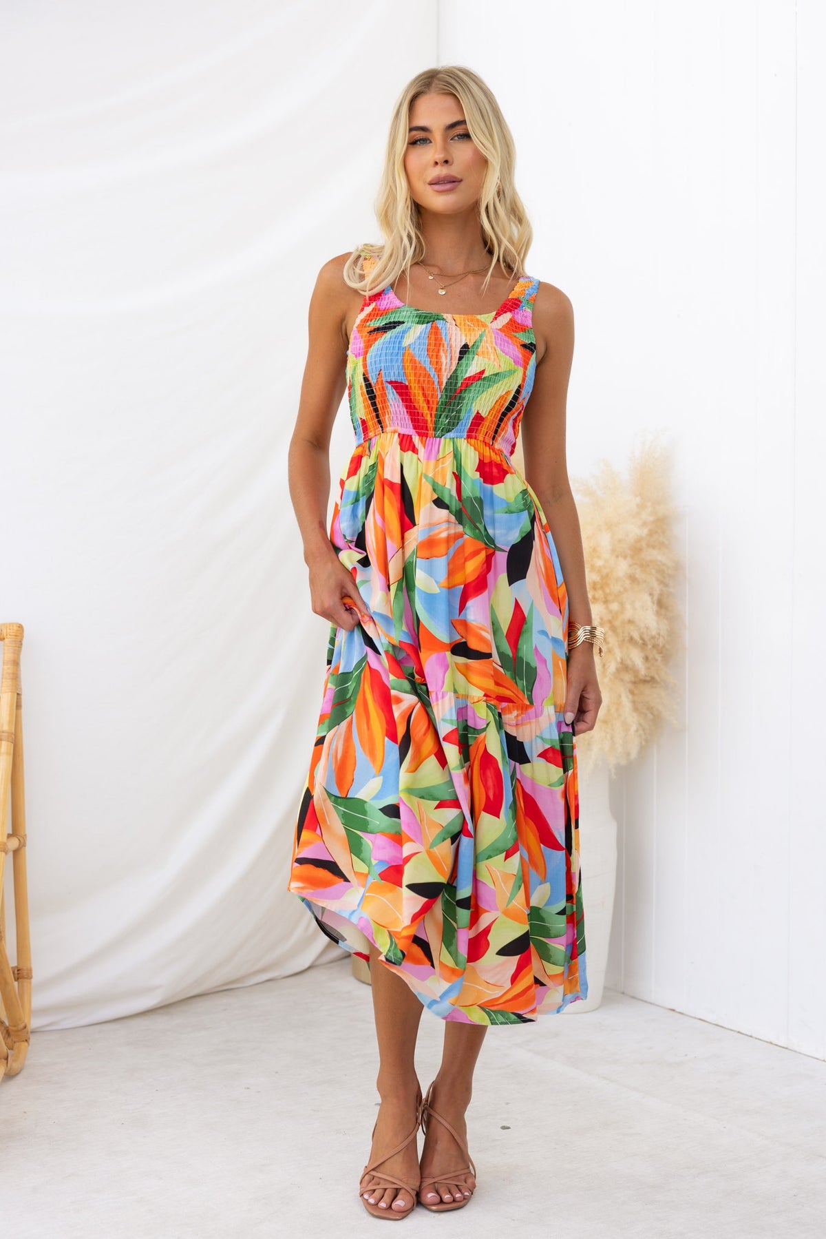 Model wearing Lemi Midi Dress with colorful floral print, round neckline, and pockets, styled in a bright setting.
