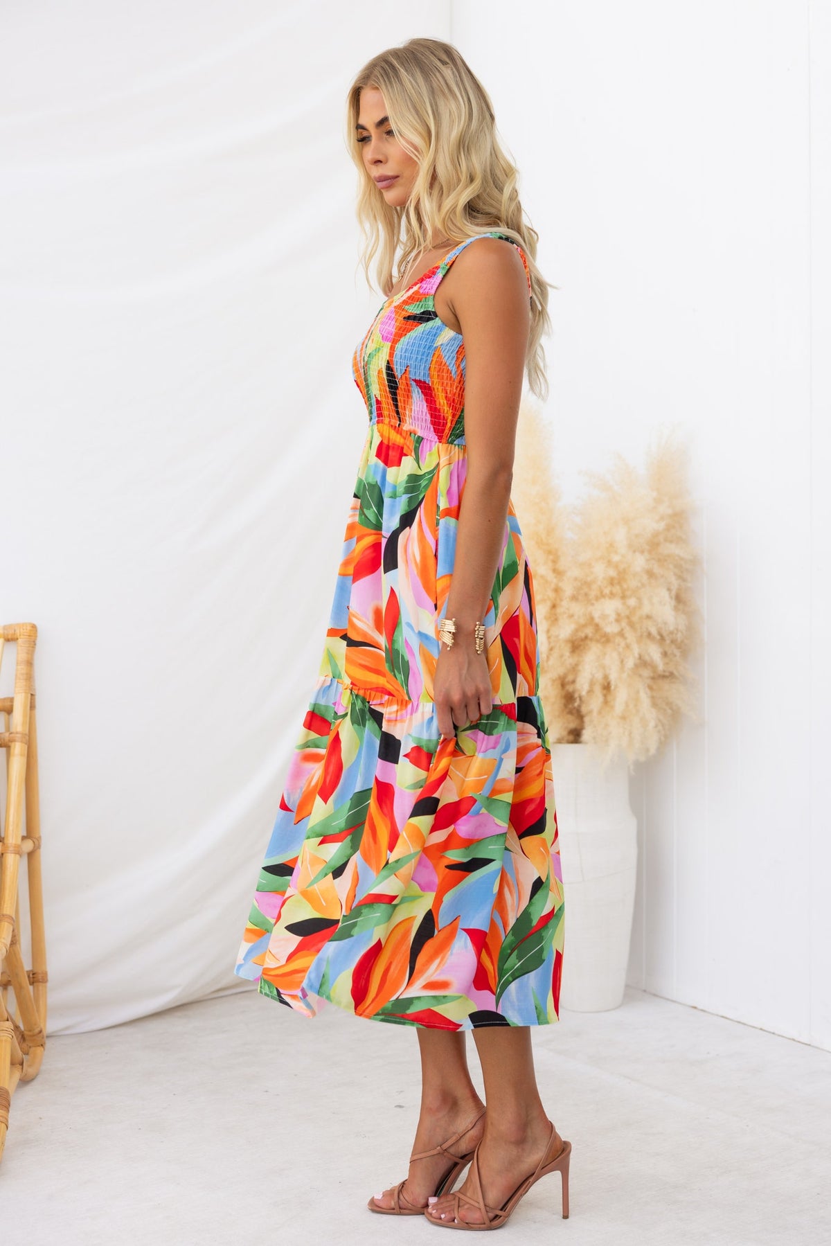 Model wearing the Lemi Midi Dress featuring a vibrant floral print and a round neckline, styled with sandals.