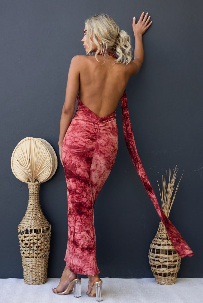 Back view of a woman in a multi-colour maxi dress with an open back and wrap detail, styled with boho decor.