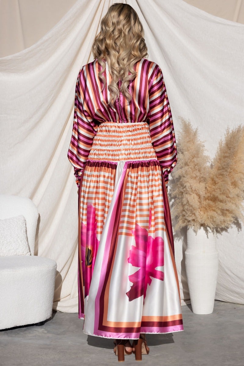 Model wearing the Flaria Maxi Dress featuring a colorful design and batwing sleeves, shown from the back.