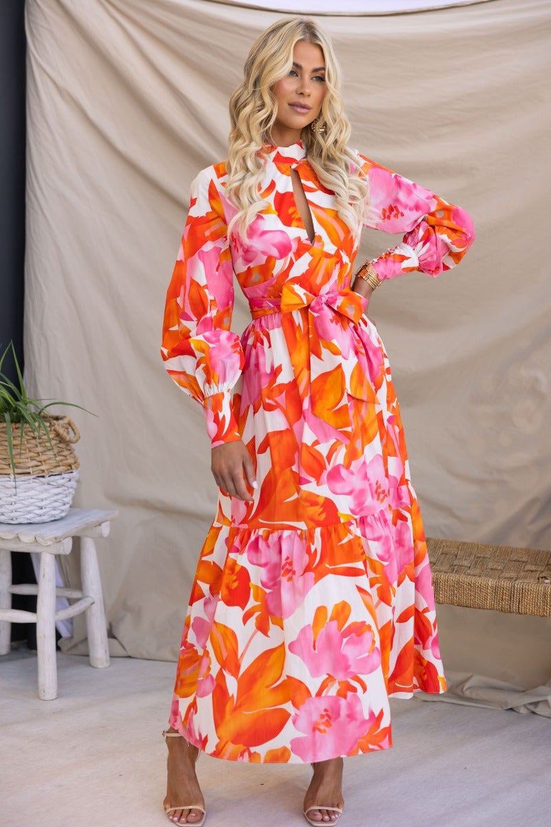 Woman in floral print Ikoma maxi dress with high neckline and cut-out, styled with removable fabric tie.