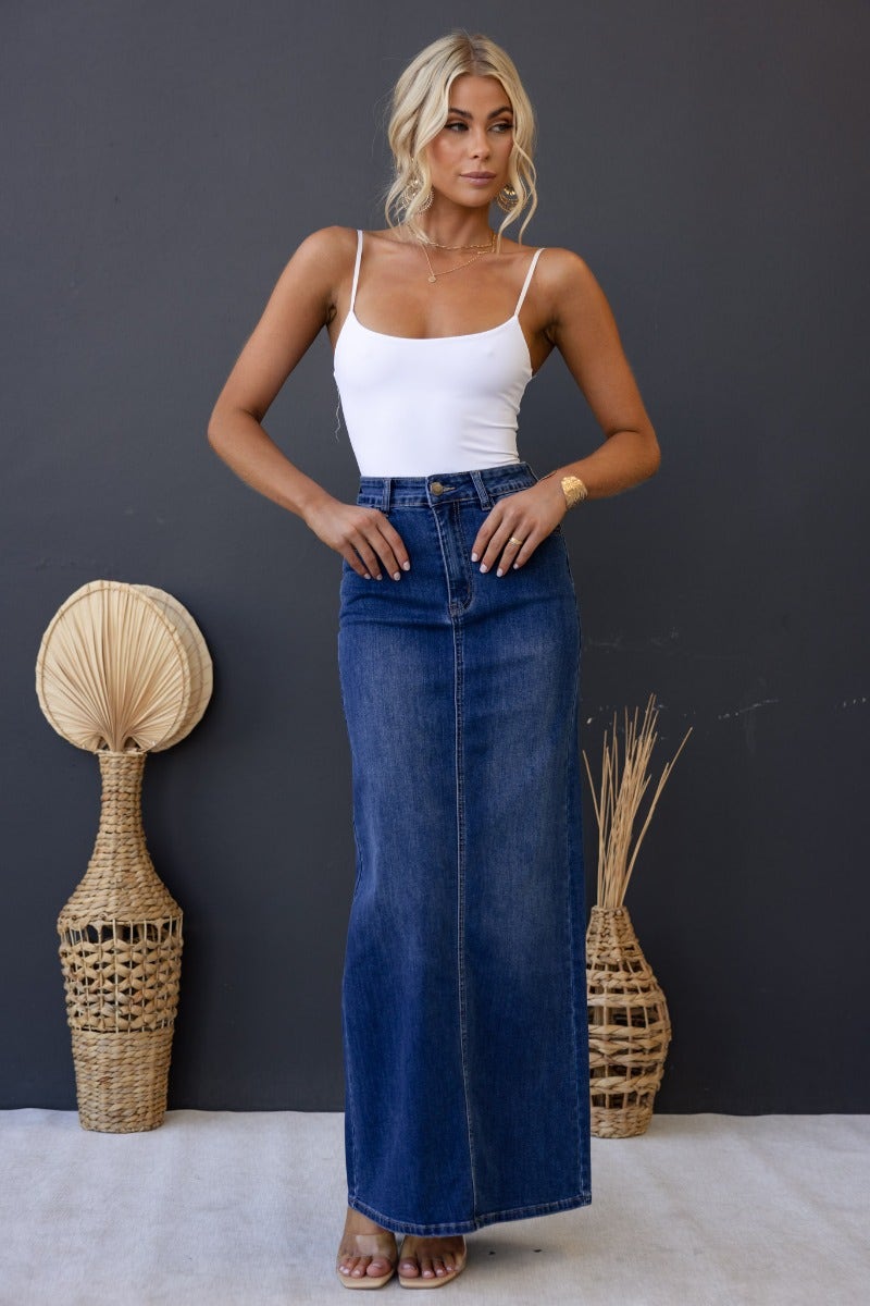 Model wearing Xano Denim Maxi Skirt, mid-high waist with pockets, showcasing a casual and stylish look against a simple backdrop.