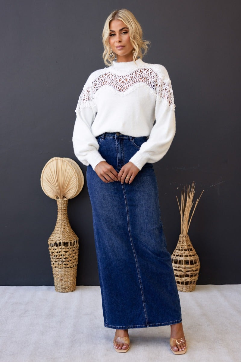 Model wearing a white Kyoto Jumper with lace detail, paired with a denim maxi skirt against a minimalist backdrop.