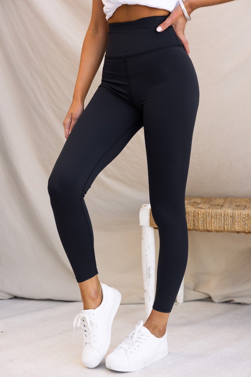 Mally black leggings with a mid-high waist and wide waistband, modeled with a standard fit and firm stretch material.