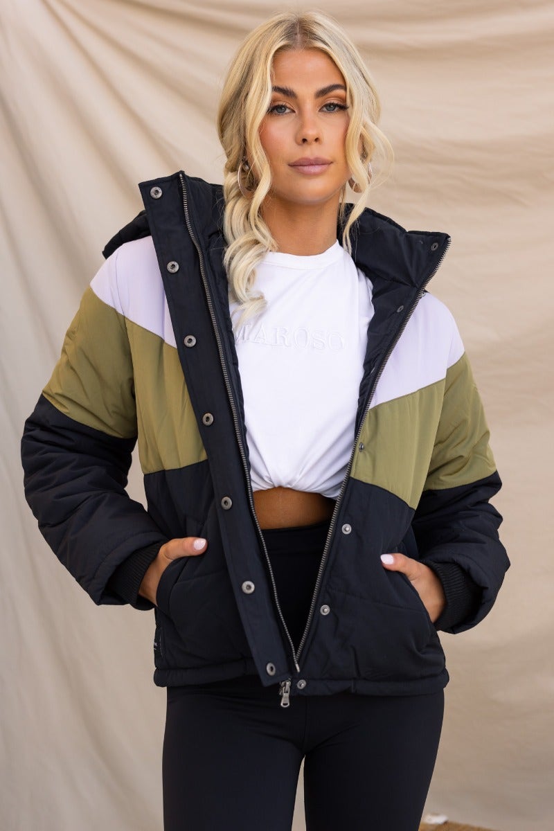 Charis Puffer Jacket featuring a black, green, and white color block design. Model wearing with removable hood, zip front, and pockets.