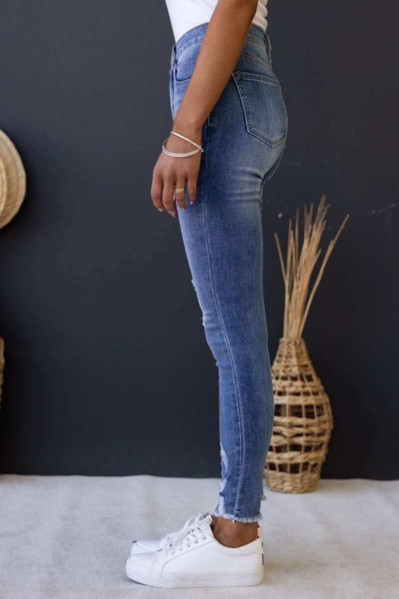 Side view of Qilli distressed denim jeans with raw hem, showcasing a standard fit and stretch material.