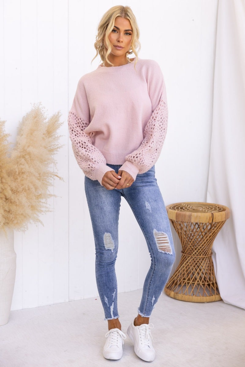 Keilor Jumper in soft pink, featuring open weave knit sleeves, styled with distressed jeans and white sneakers.