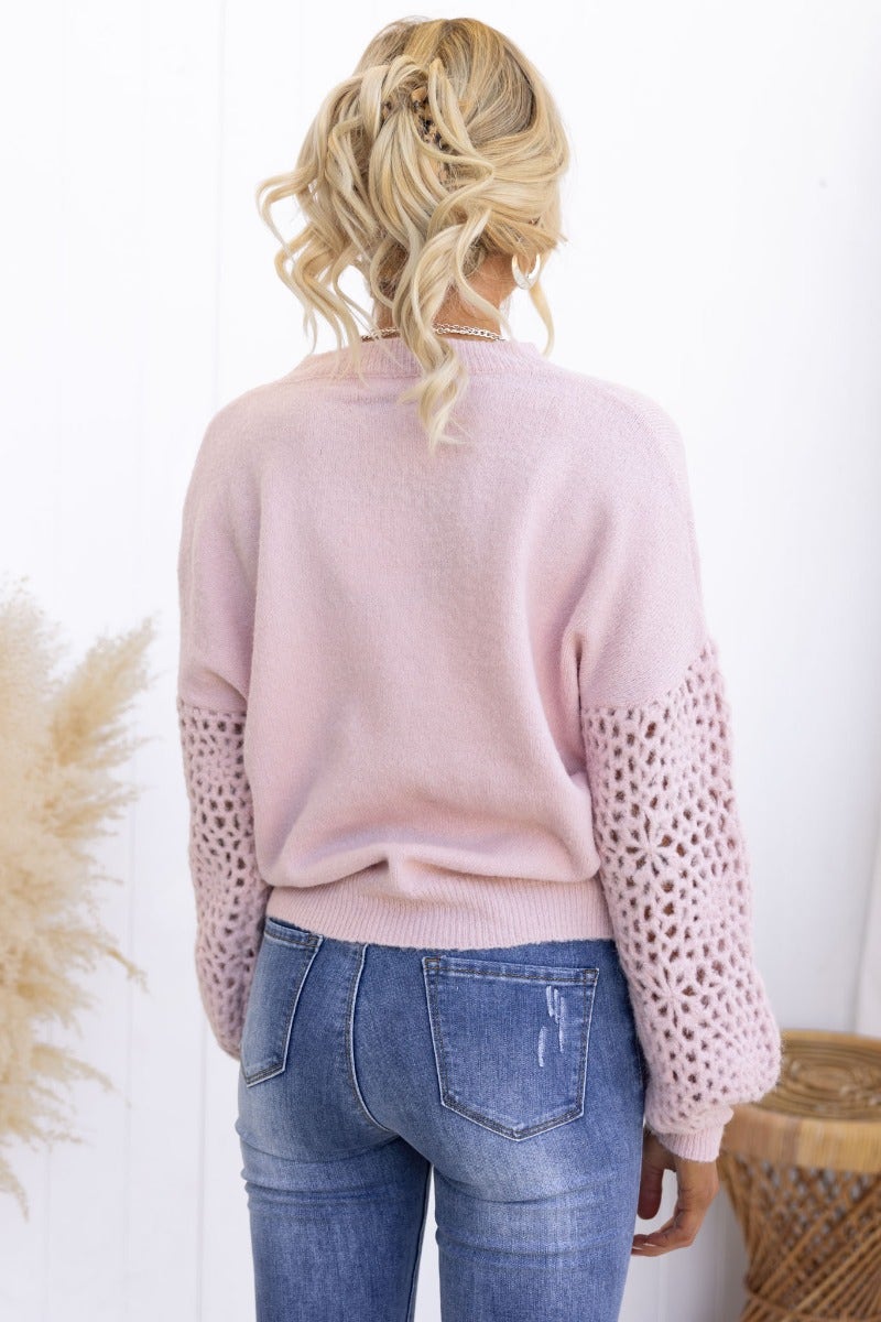 Back view of a pink Keilor Jumper featuring open weave knit sleeves, styled with denim jeans.