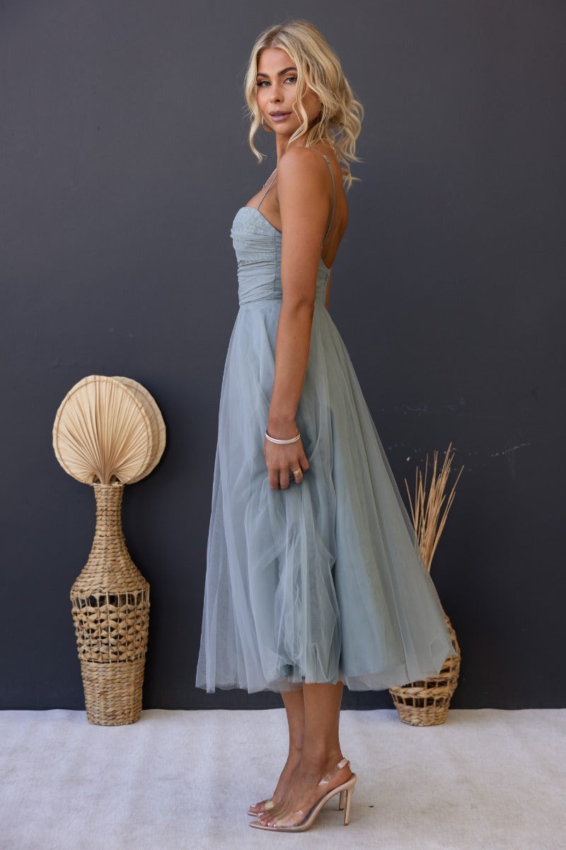 Model wearing a Genevie Midi Dress in soft blue tulle with adjustable straps and padded bust, styled for a relaxed look.
