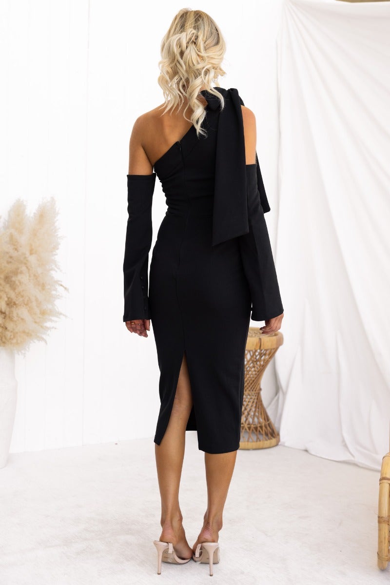 Back view of a black Ellidy midi dress with a one-shoulder neckline, bow detail, and a back split.
