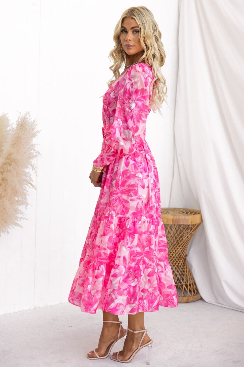 Model wearing a pink floral print midi dress with V-neckline and removable belt, showcasing a relaxed fit.