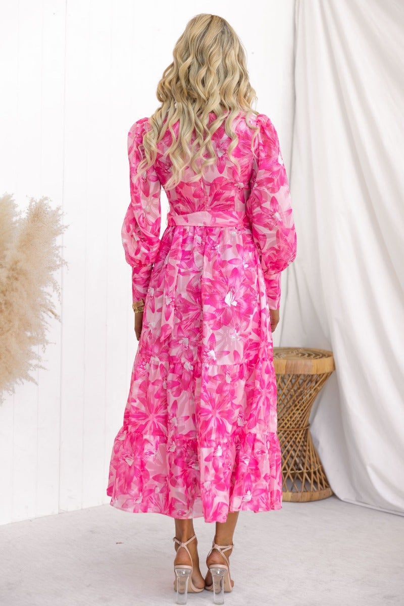 Back view of a floral print Ocean Beach midi dress with a V-neckline and puffed sleeves, styled with a removable belt.