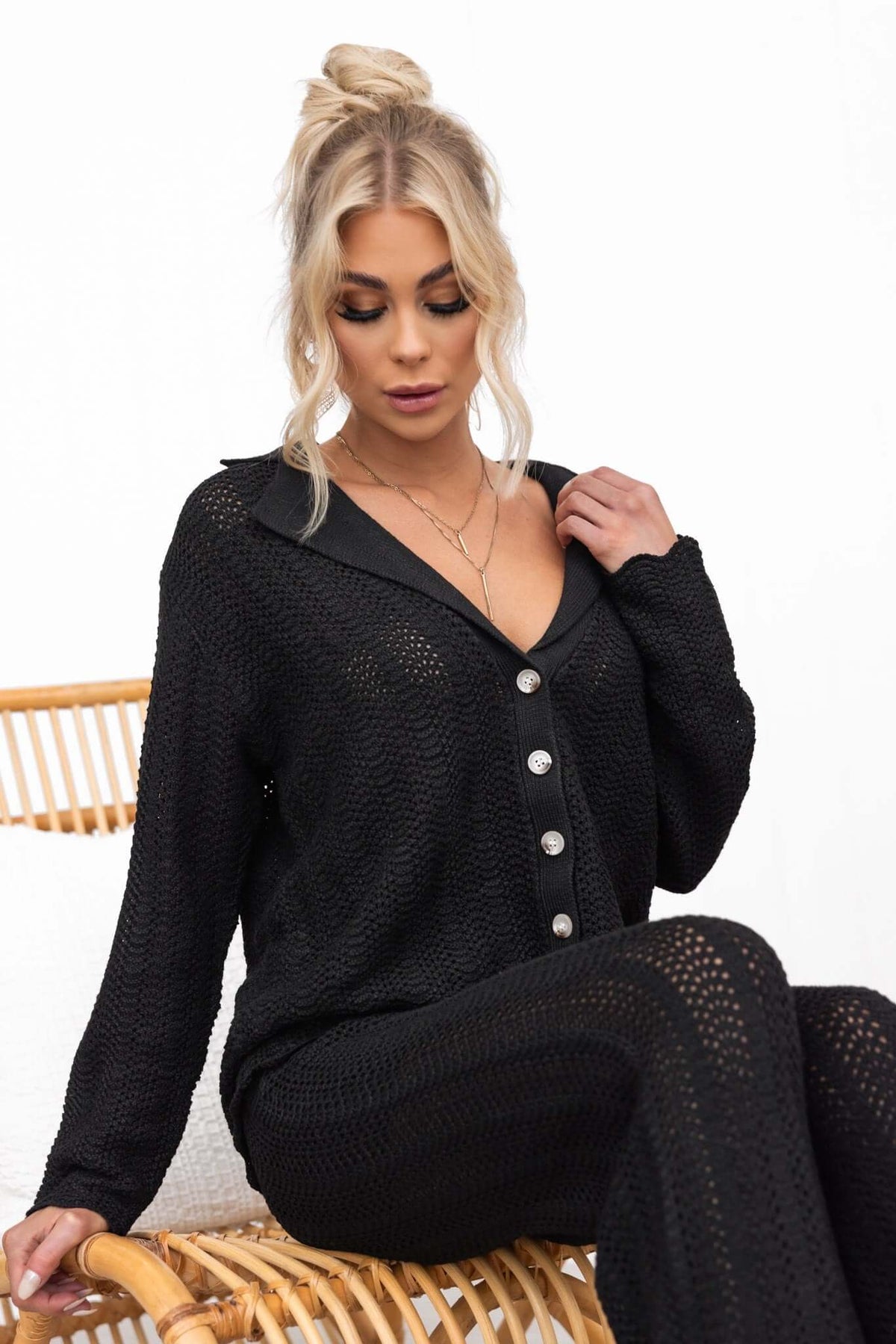 Model wearing a black button-up Moline shirt made from semi-open weave knit material.